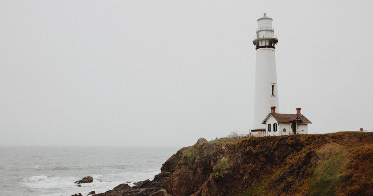 A white lighthouse on a foggy cliff — a trust signal when the view is murky
